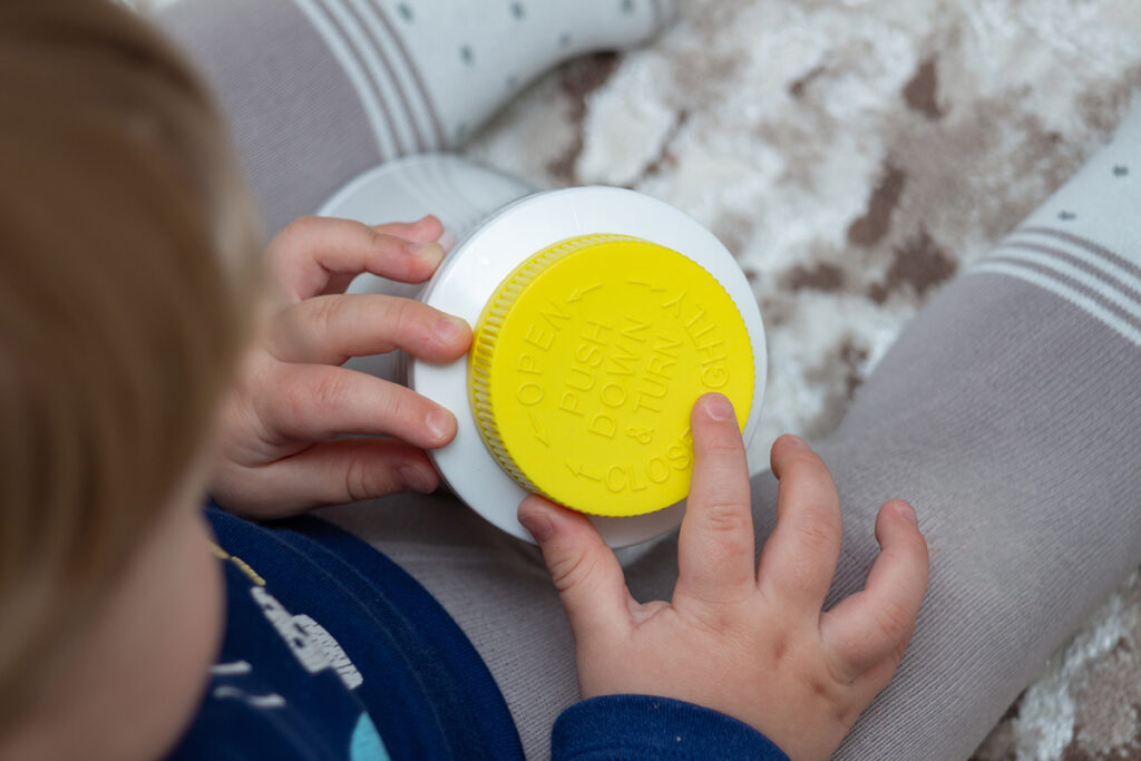A child playing with a container safely because of child-resistant packaging.
