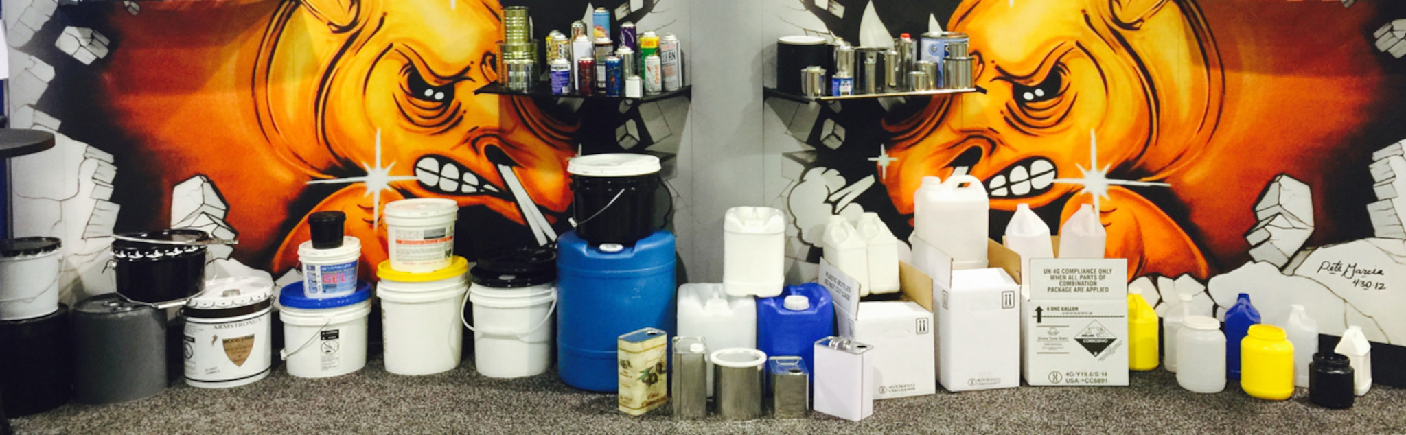 A wide ranging display of various product containers in front of a mural at Rhino Container headquarters in Chino, CA.