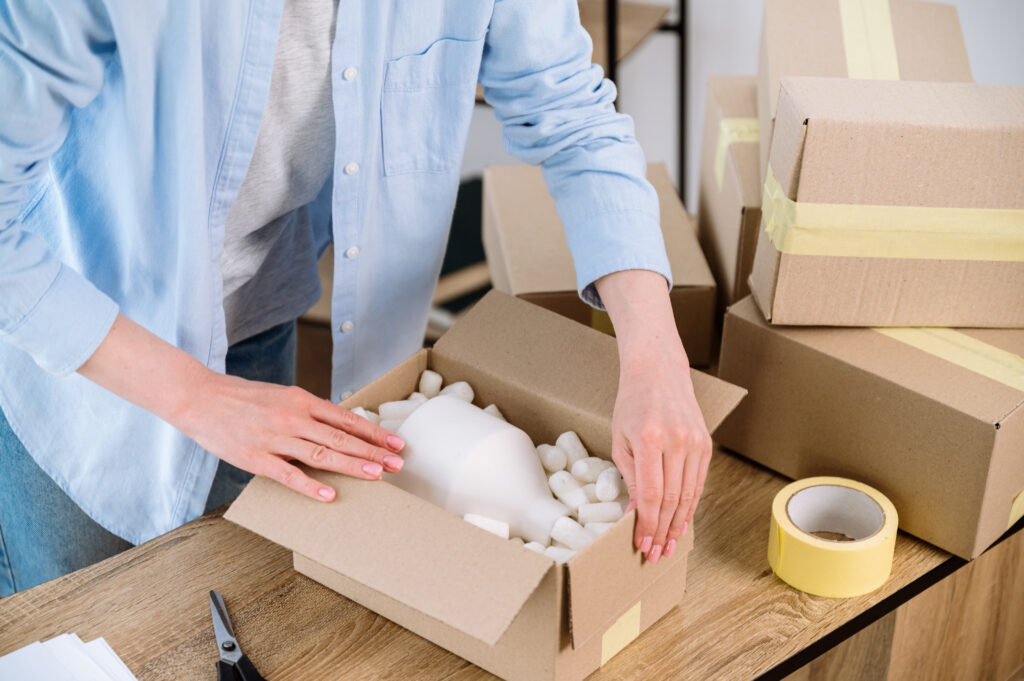A person preparing a product for shipping demonstrating how seals, shrink bands, and tear strips enhance consumer confidence.